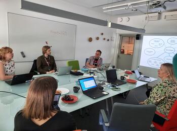 Team sitzt um einen Tisch und diskutiert