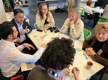 Teilnehmer sitzen um einen Tisch und diskutieren