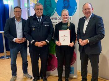 Oberbürgermeister Christian Specht (r.) überreicht mit Polizeipräsident Siegfried Kollmar (2.v.l.) und Sicherheitsdezernent Dr. Volker Proffen (l.) die Auszeichnung an Corinna Führer.