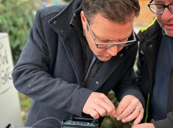 Arbeiten am Glasfaser-Kabel: Bürgermeister Dr. Volker Proffen darf sich unter fachkundiger Anleitung selbst im Spleißen versuchen.