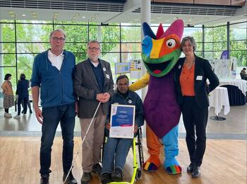 Dr. Klaus Wolff und Karl-Heinz Schneider vom Badischen Blinden- und Sehbehindertenverein V.m.K. (BBSV), Heinrich Schaudt von der Arbeitsgemeinschaft Barrierefreiheit Rhein-Neckar e.V, das Maskottchen Chämy und Ursula Frenz, Beauftragte für die Belange von Menschen mit Behinderungen bei der Preisverleihung in Ulm