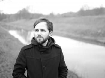 Florian Wacker auf einem Schwarz Weiß Bild. Er läuft an einem Fluß entlang.