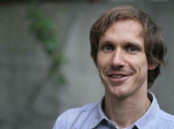 Tobias Steinfeld lächelt in die Kamera und trägt ein blaues Hemd.