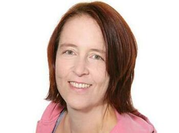 Rike Reiniger in einem pinken Pullover lächelt in die Kamera.