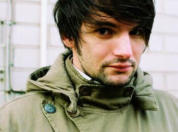 Sasa Stanisic trägt einen Parka, seine Haare fallen über sein linkes Auge.