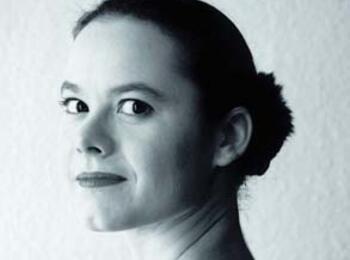 Schwarz-Weiss-Foto: Antje Wagner, die über ihre linke Schulter zurück, in die Kamera blickt.