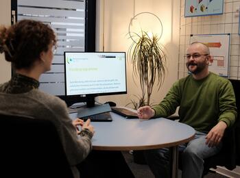 Mann berät eine Frau am Schreibtisch