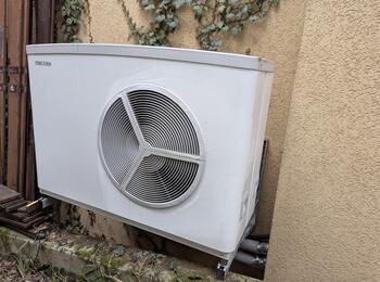 Wärmepumpe an begrünter Hauswand