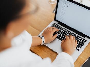 zwei Hande, die an einem Notebook etwas tippen, der Mensch verschwommen