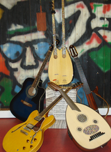 Ein Foto zeigt verschiedene Zupfinstrumente vor einer Wand mit Graffiti.