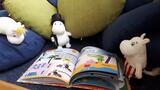 Ein aufgeschlagenes Bilderbuch und drum herum mehrere Kissen und Mumin-Stofftiere