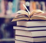 Aufgeschlagenes Buch auf Bücherstapel