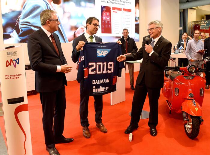 Der Maimarktrundgang führte auch an den Stand der MVV, wo Staatssekretär Baumann ein Trikot der Adler erhielt.