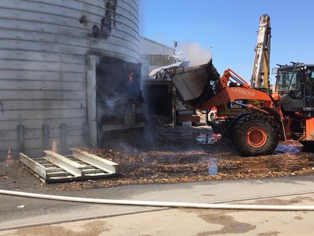 Mit einem Radlader werden die Holzschnitzel ins Freie gezogen und dort gelöscht.