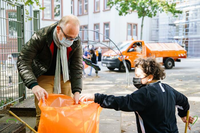 Herr Bürgermeister Grunert unterstützt einen Grundschüler der Johannes-Kepler-Grundschule beim Abfall sammeln.