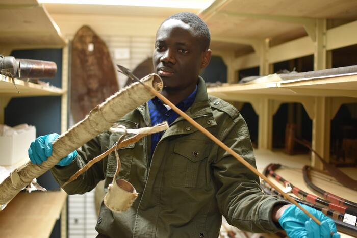 Mann mit Köcher und Pfeilen zwischen regalen