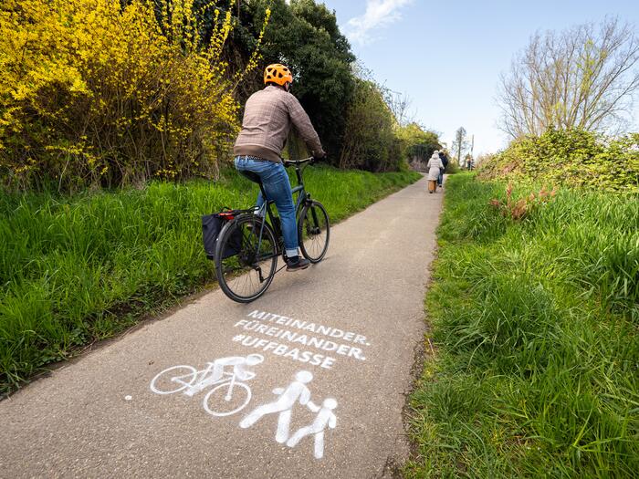 Fahrrad fährt auf Radweg. Kreidespray auf Fahrbahn weist auf ein rücksichtsvolles Miteinander hin