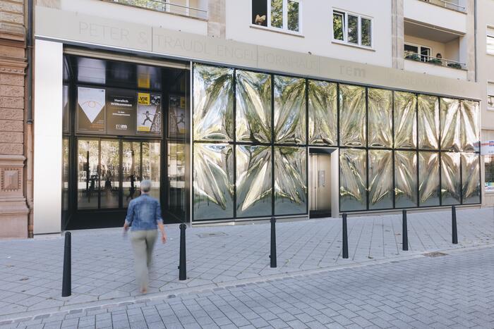 Eine Frau läuft auf den Eingang eines Museums mit auffälliger Glassfassade zu